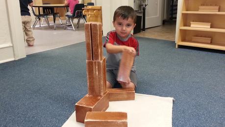 A boy sitting beside a tower of wooden blocks